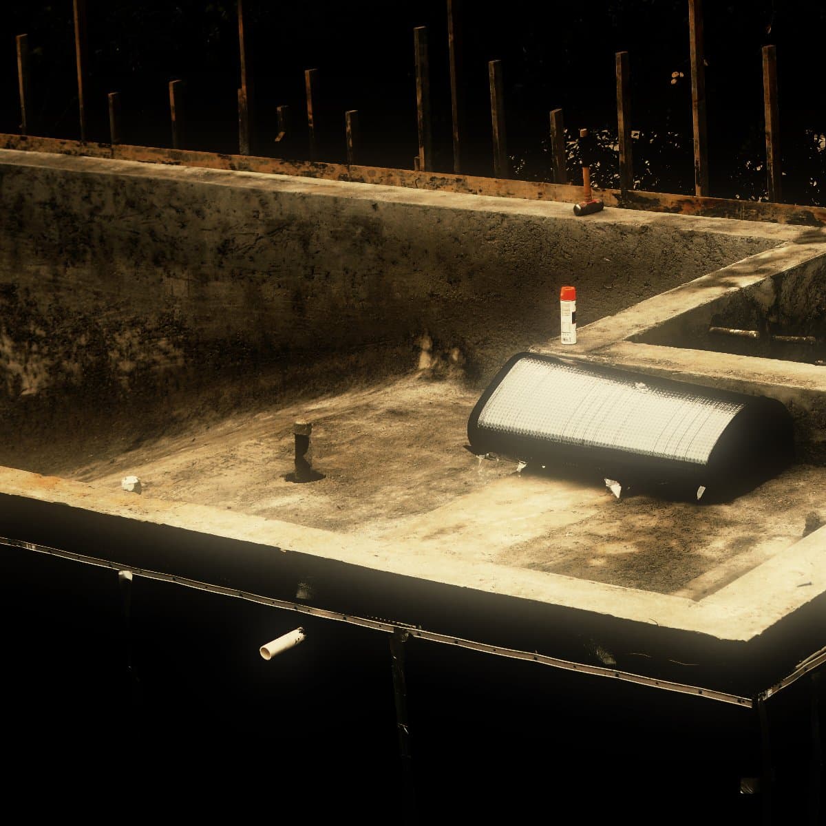 The stripped concrete basement and pool structure, its formed faces clean and its outer face sheeted in waterproofing membrane and drainage board