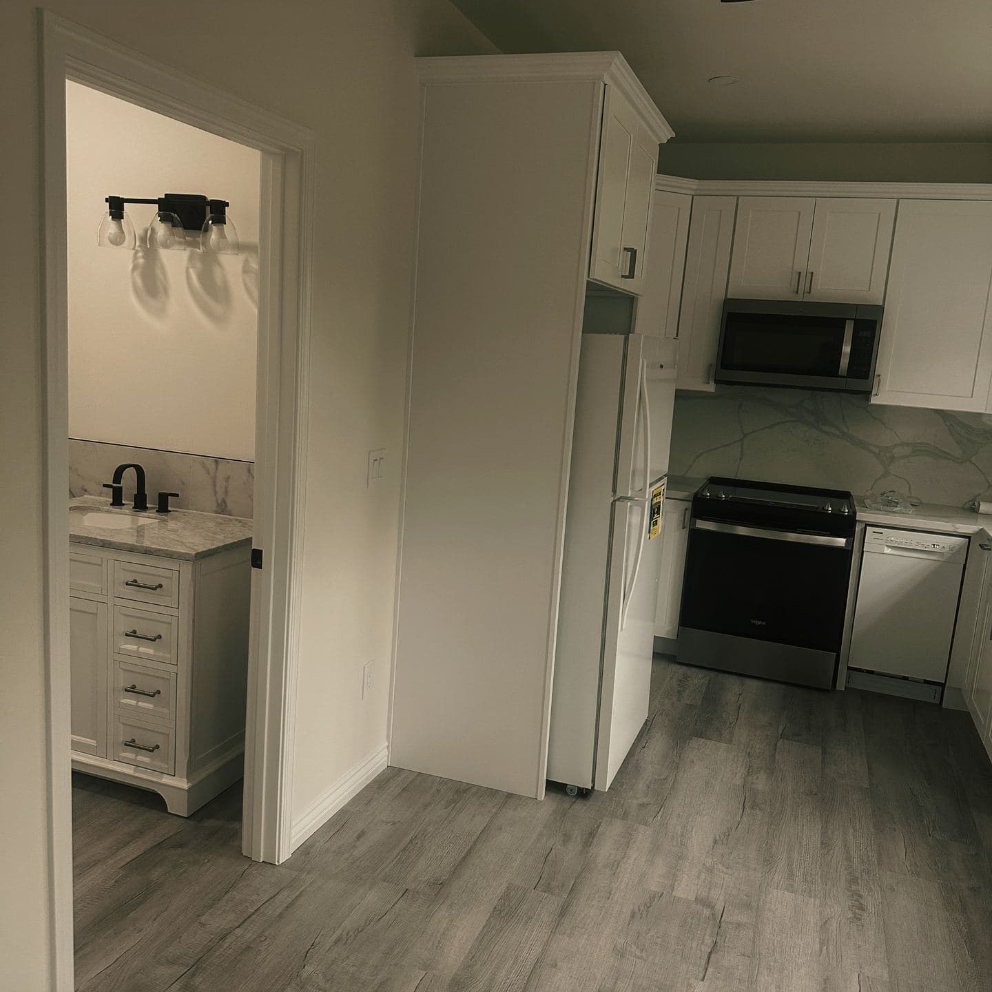 The kitchen of the Newbury Park unit seen from the main room, with the bathroom doorway open beyond it