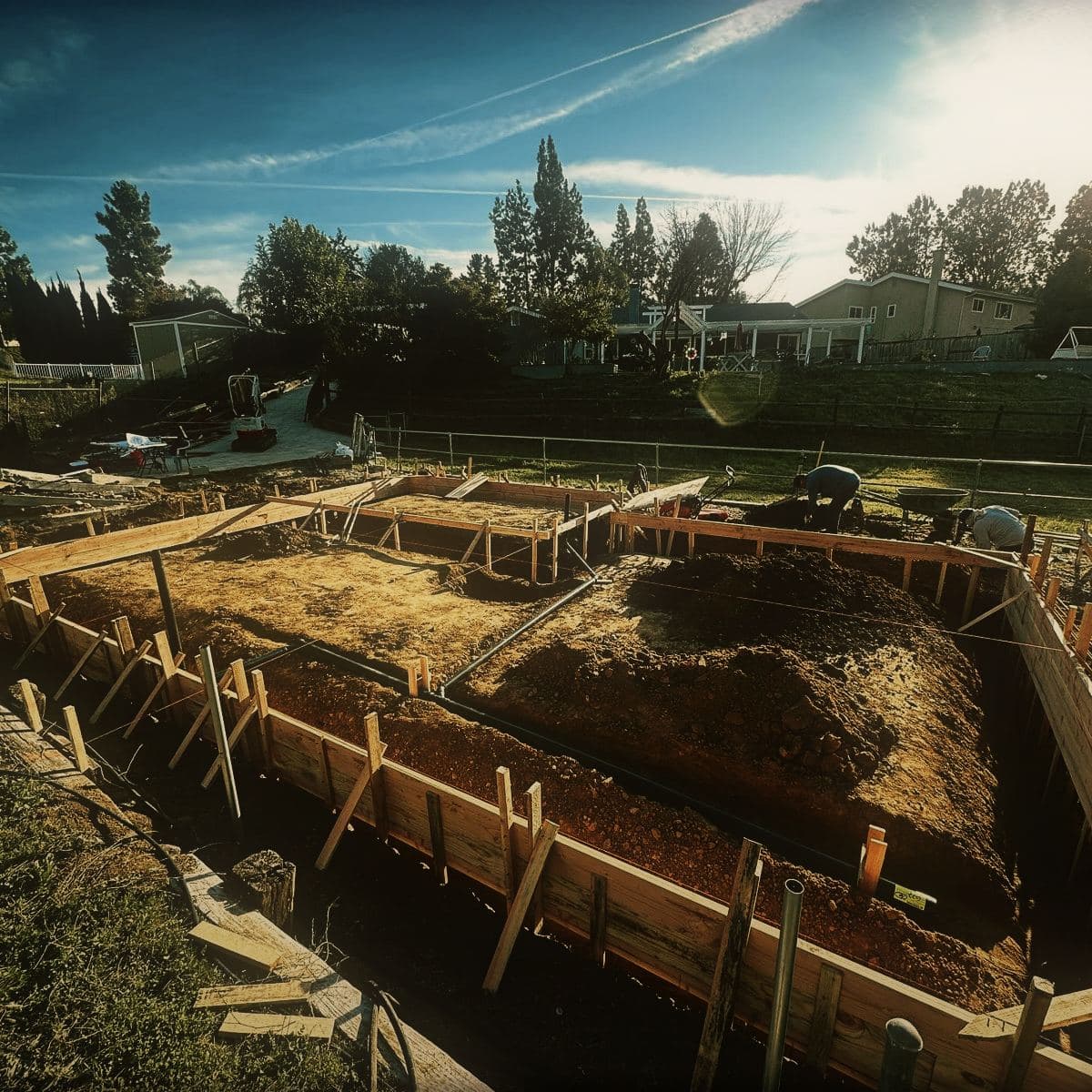 Footing trenches dug and formed in timber around the perimeter of the building footprint, reinforcement laid in the bottom of each run