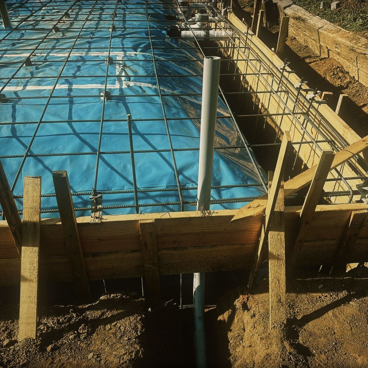 Reinforcing steel tied through the formed footings with sheeting laid across the slab area behind it
