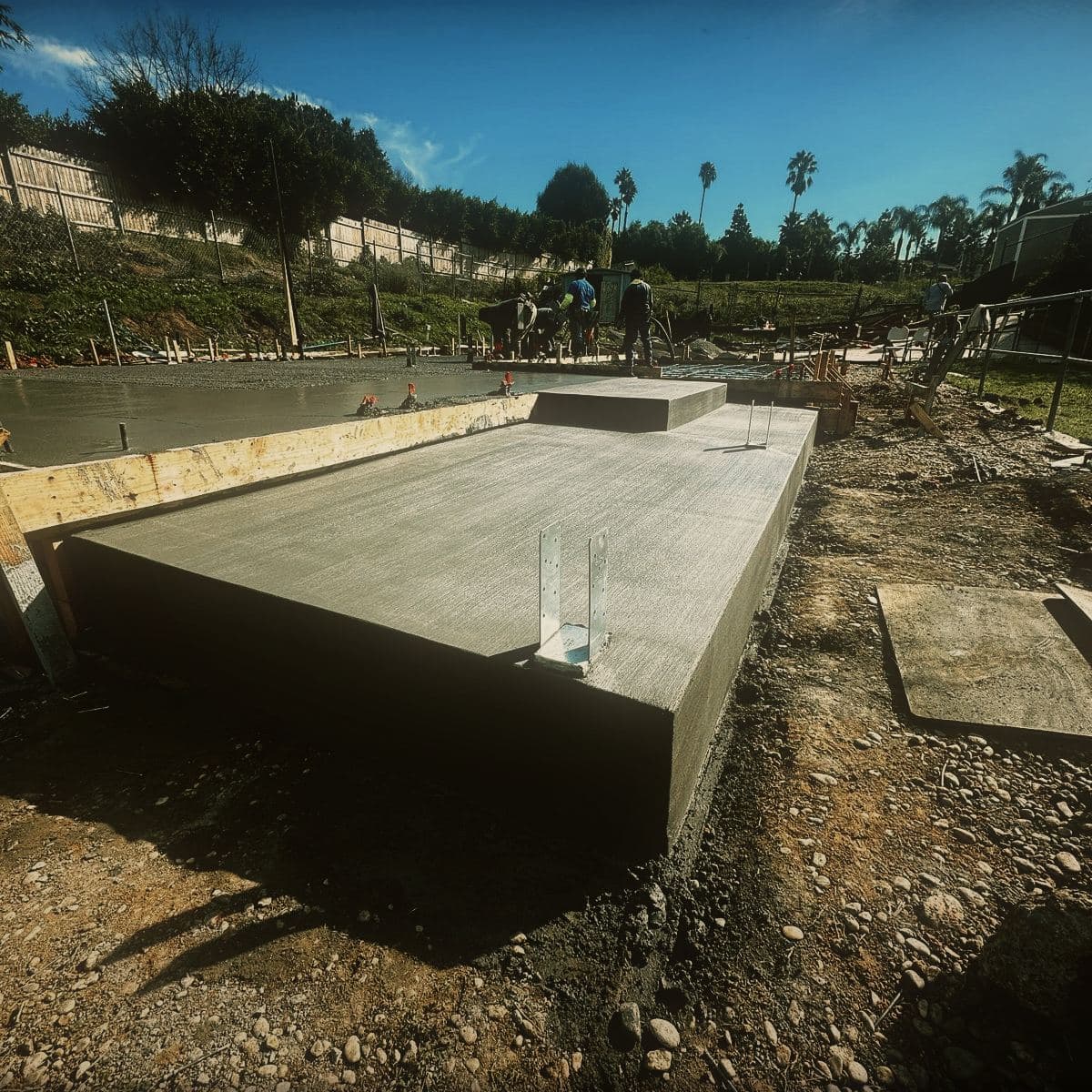 The poured and finished concrete slab of the guest house with its edge formwork still in place
