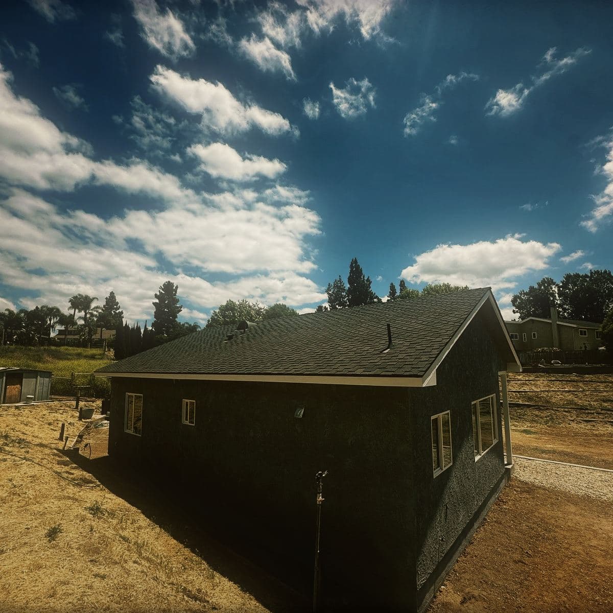 The completed guest house seen across the lot, showing its full length and the open ground it was built on