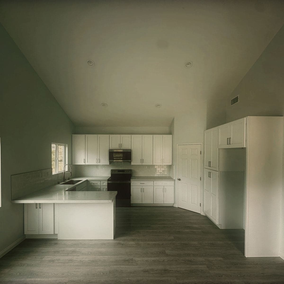 The finished kitchen of the guest house, fitted cabinets and appliances beneath the open ceiling