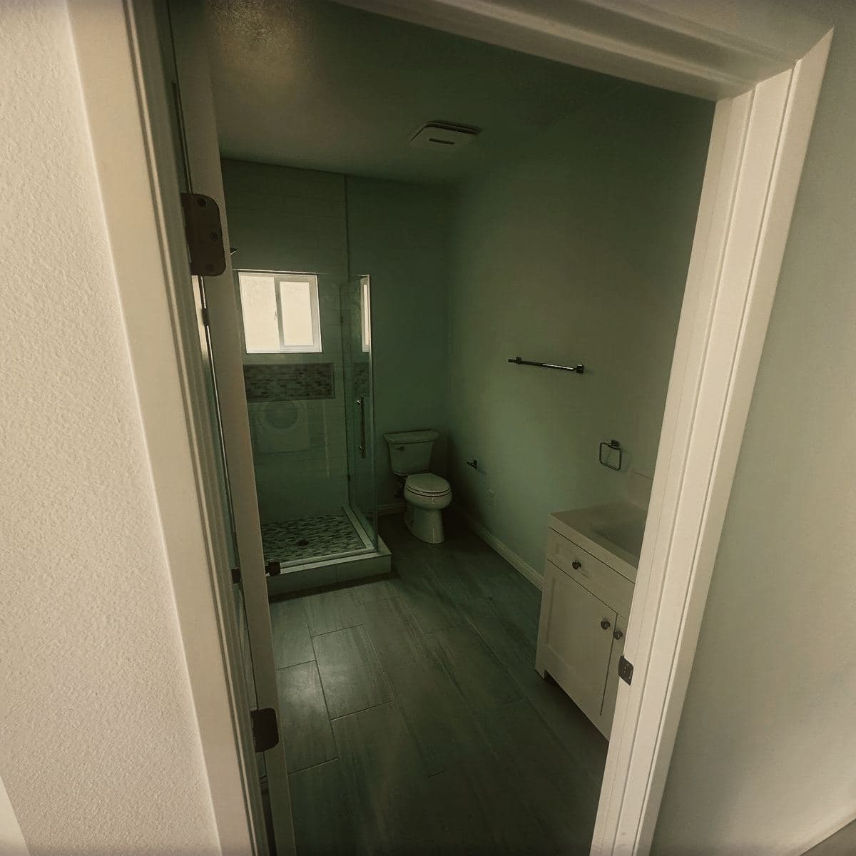 The finished bathroom of the guest house, tiled with a vanity unit and a window above