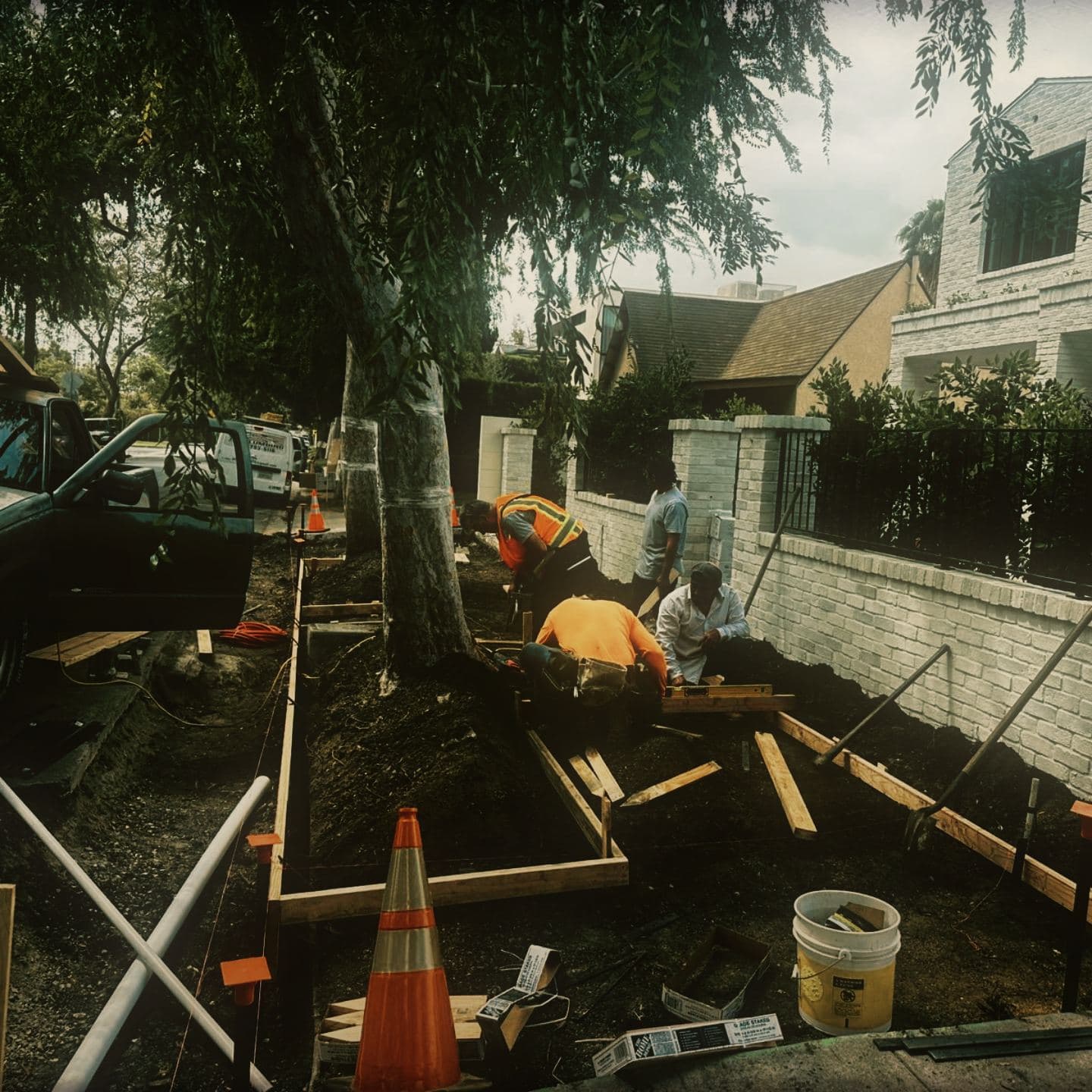 Crew setting formwork along the excavated right-of-way at Westmount, one checking it with a spirit level while another cuts lumber