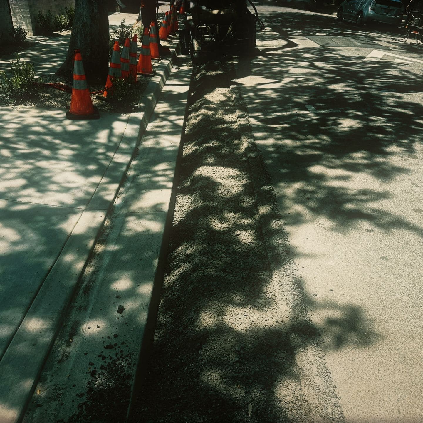 The saw-cut trench along the gutter at Westmount cleaned out and squared off ready for the asphalt patch, running the length of the frontage behind a cone line
