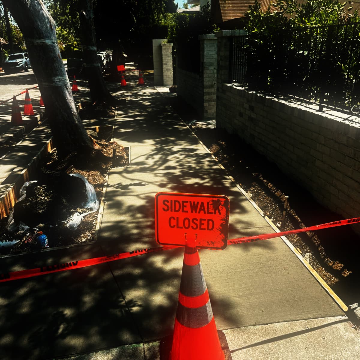 A newly placed sidewalk running the length of a frontage with the closure signage and barrier tape still in place across it