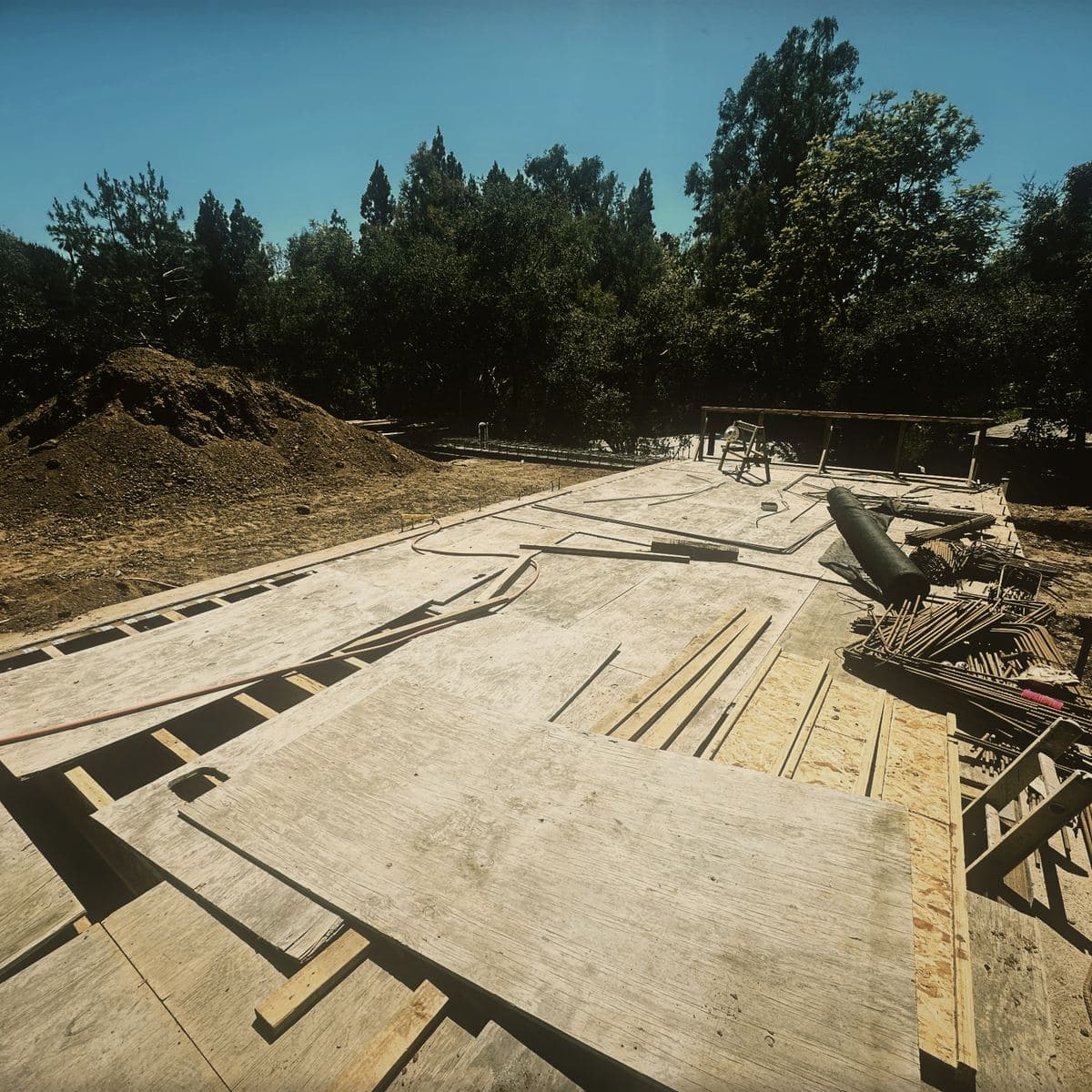 The structural slab down over the Brentwood basement structure, waterproofing strips laid across the deck and reinforcing steel stacked ready at the edge