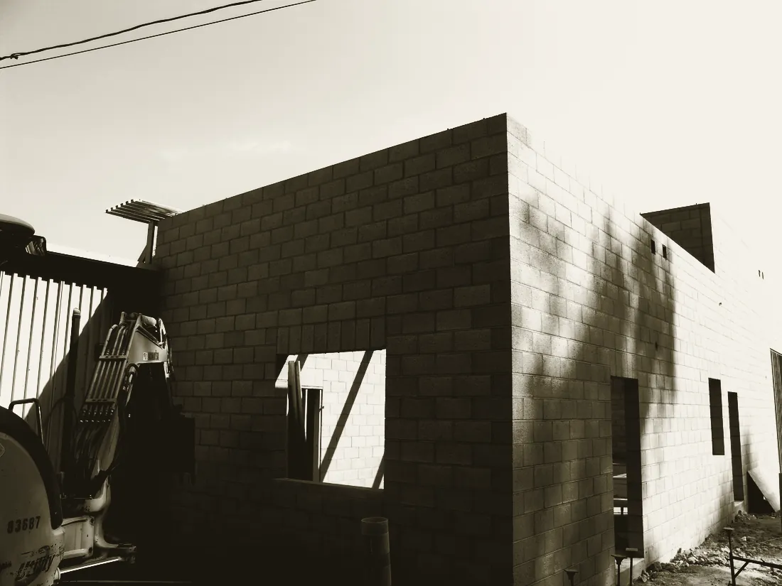 Block walls and an excavator working alongside the part-built structure