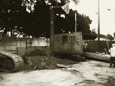 An excavator setting shoring plates along the trench line
